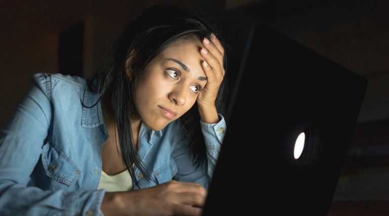 student sitting in the dark looking upset at computer screen
